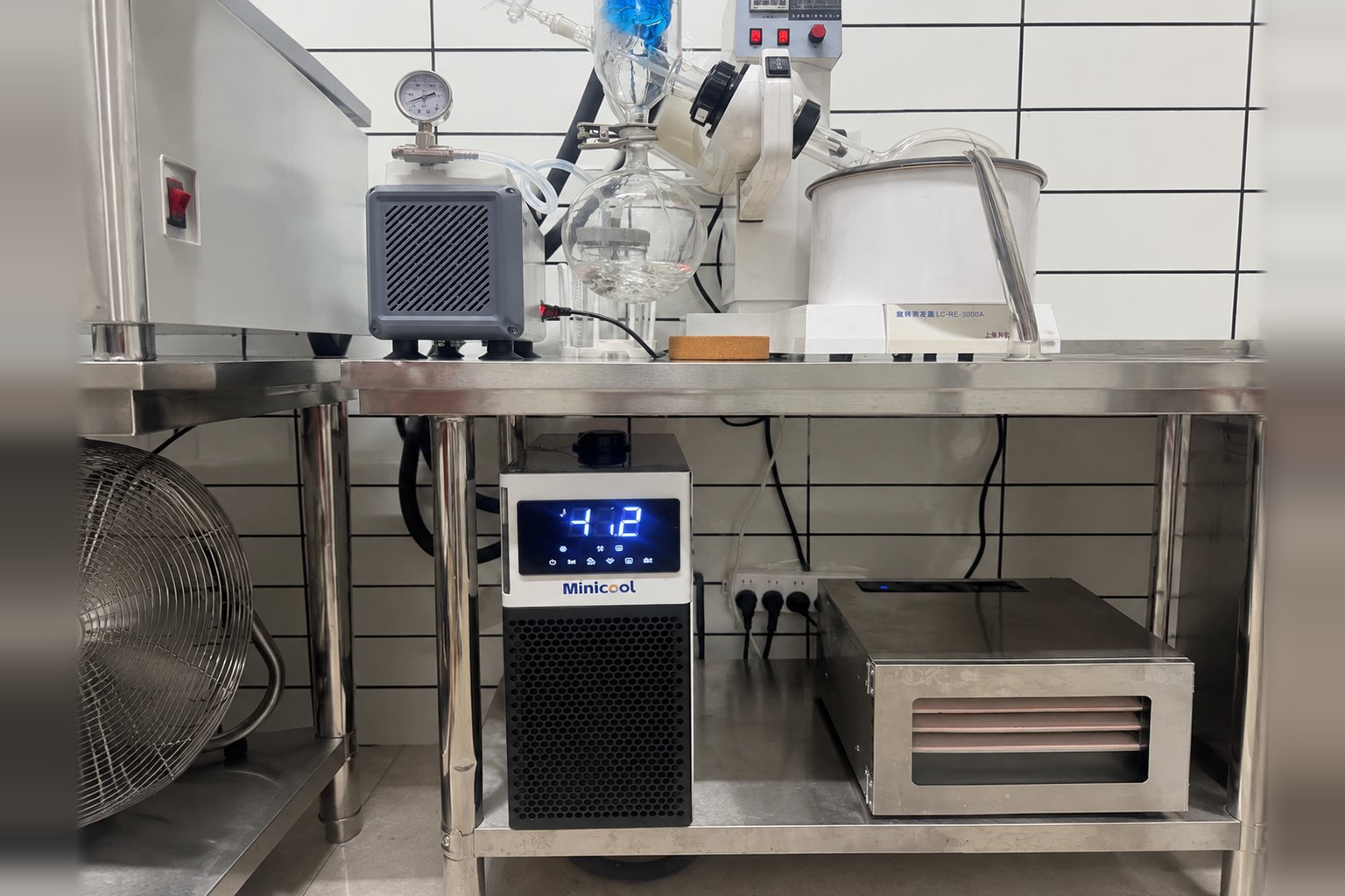 MiniCool recirculating chiller on the lower shelf of a stainless laboratory bench below a rotary evaporator