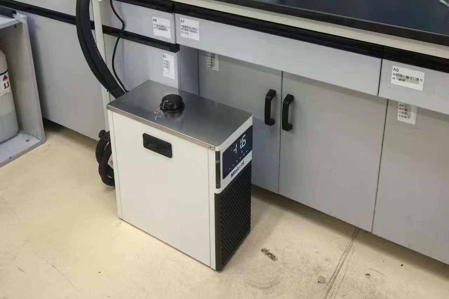 Closed-loop benchtop chiller installed beside a laboratory bench with insulated coolant lines